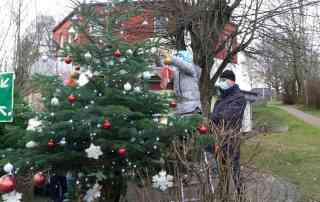 Kinderdorfkind und Einrichtungsleiter beim Tannenbaum schmücken