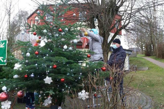 Kinderdorfkind und Einrichtungsleiter beim Tannenbaum schmücken