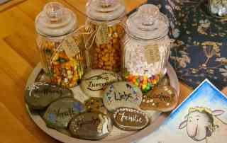 Süßigkeiten in schönen Gläsern verpackt und Botschaften auf Steine geschrieben