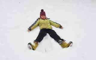 Kind erzeugt einen Schneeengel im frischen Schnee