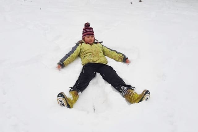 Kind erzeugt einen Schneeengel im frischen Schnee