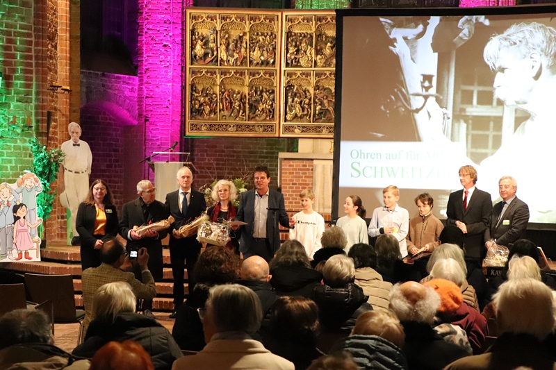 Die Akteure beim neunten Konzert „Ohren auf für Albert Schweitzer“ von links: Astrid Walter (Vorstand), Dr. Omar Mahjoub (Ehrenvorsitzender), Thomas Klapproth (Bürgermeister Hannover), Lisa Laage-Smidt (Kinderchor MARKTKIRCHE), Moderator und Organisator Jörg Grabowsky, die Sieger des Vorlesewettbewerbs der IGS Bothfeld Tobias Klingspohn, Melissa Gözen und Justus Wiesbrock mit Lukas Sampedro, Marktkirchenorganist Prof. Ulfert Smidt und Martin Kupper (Vorstand)